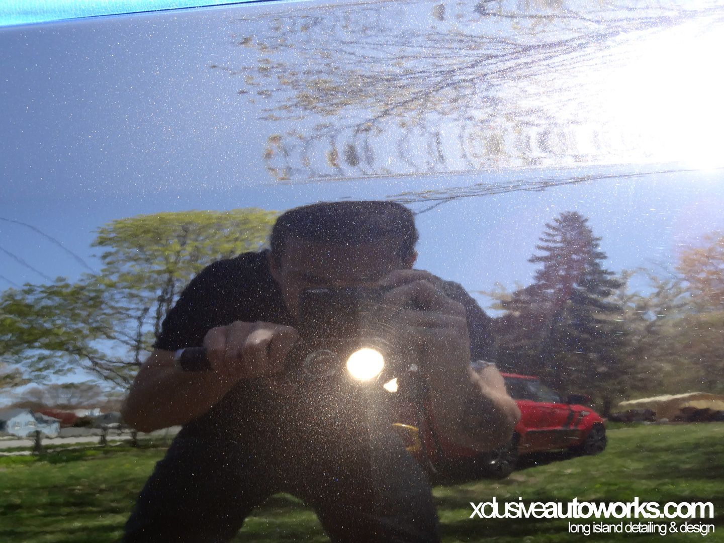 A man is taking a picture of his reflection in a car window