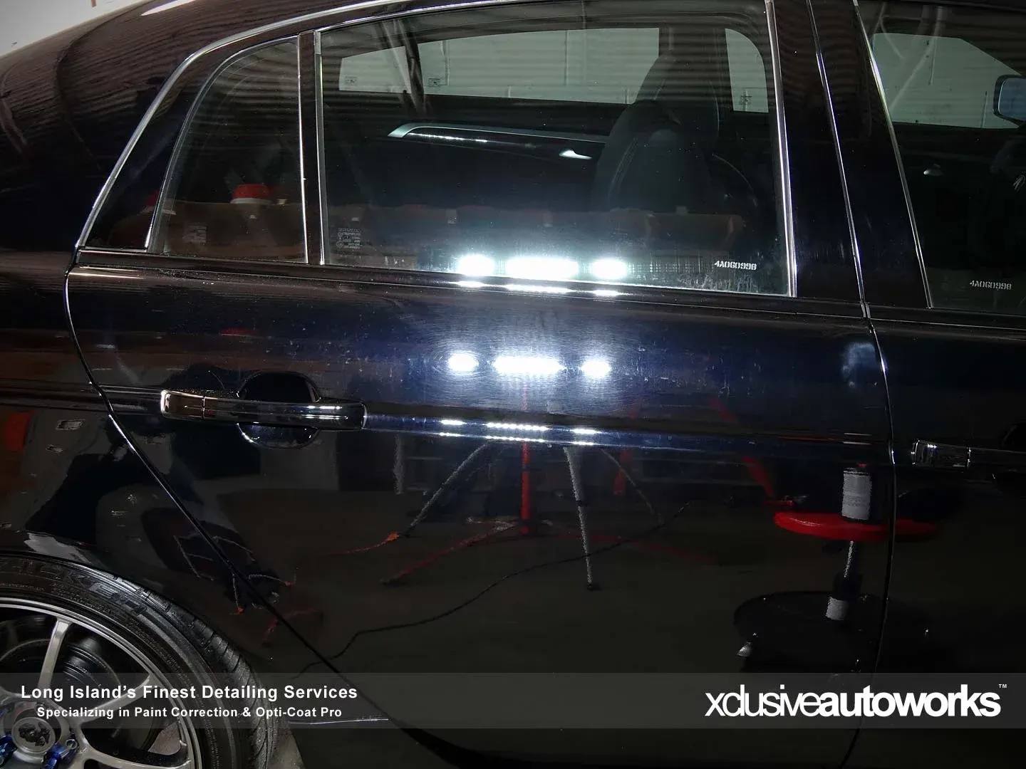 A black car is being polished by xclusive autoworks