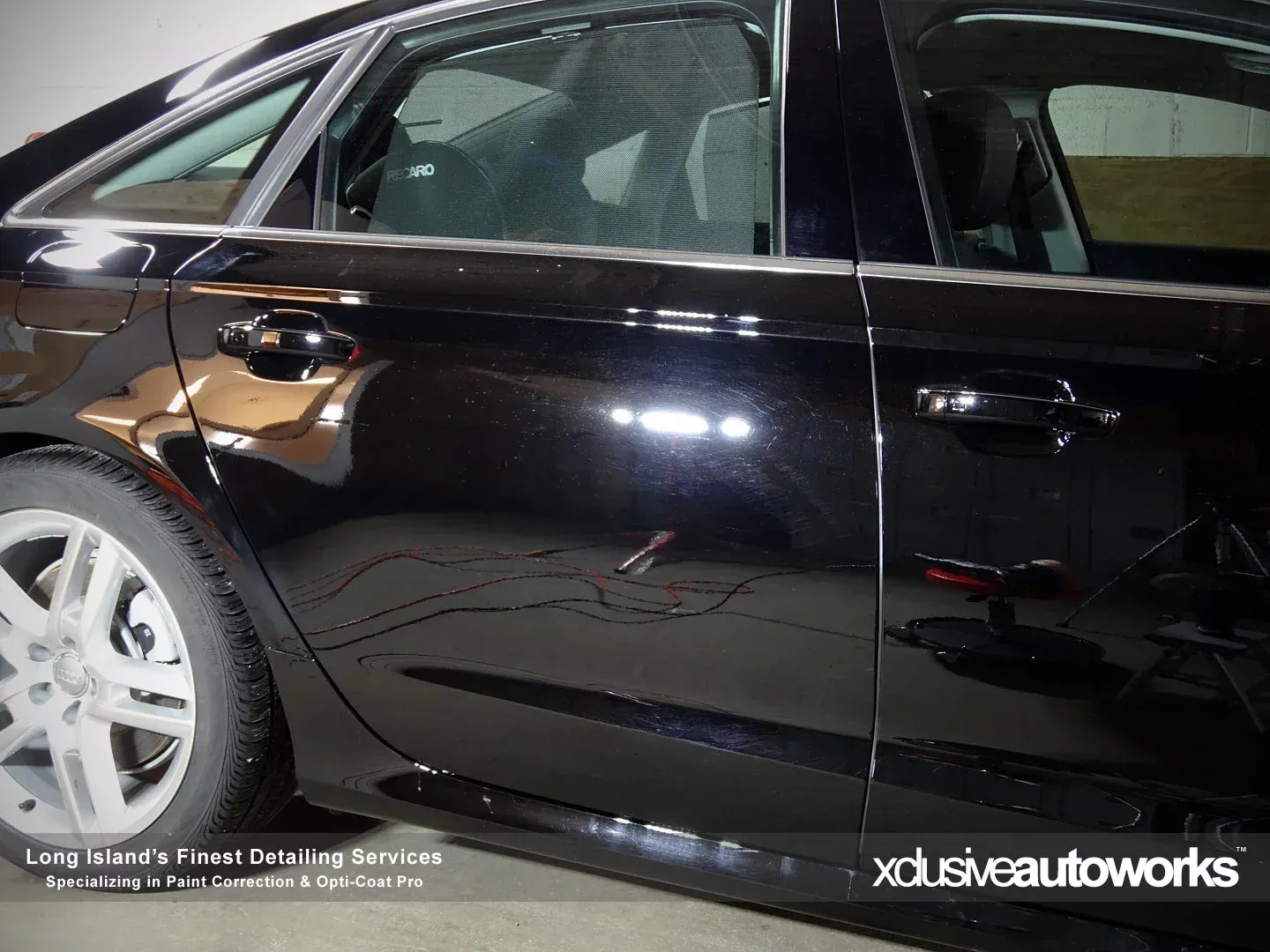 A close up of a black car with xclusive autoworks written on the side
