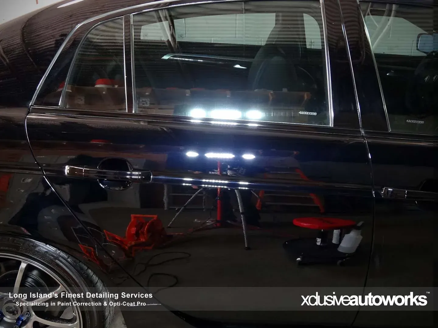 A black car is being worked on by xclusive autoworks