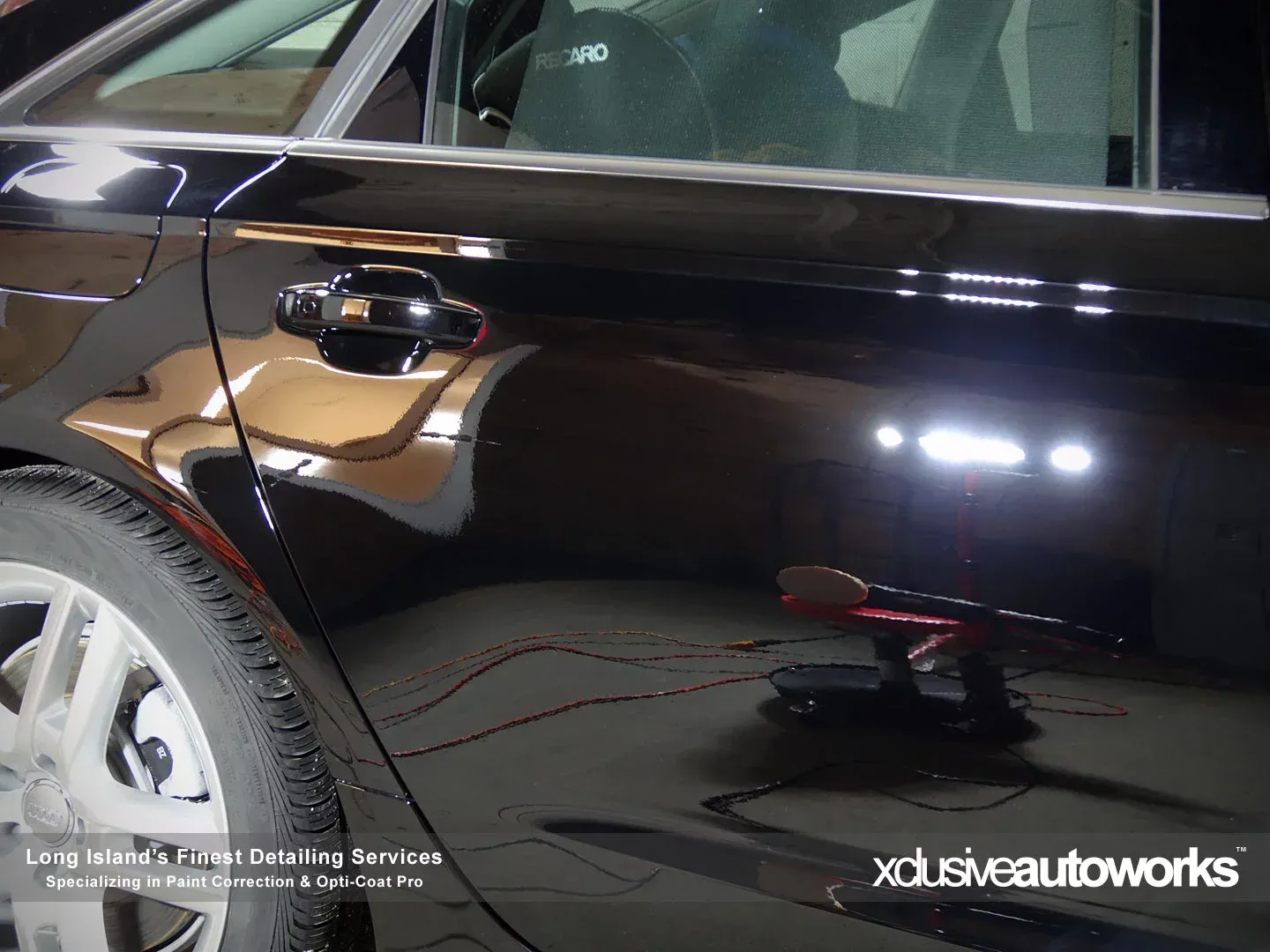 A black car is being polished by xclusive autoworks