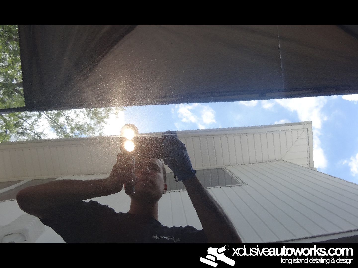 A man is taking a picture of himself in a mirror with the website xdusveautoworks.com in the corner