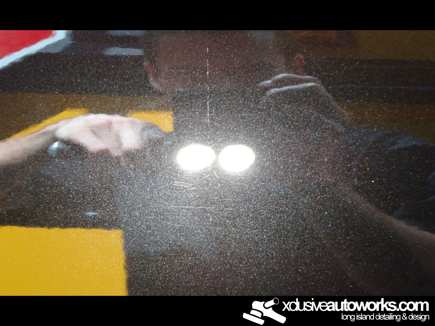 A man taking a picture of himself in a mirror with xdusveautoworks.com written on the bottom