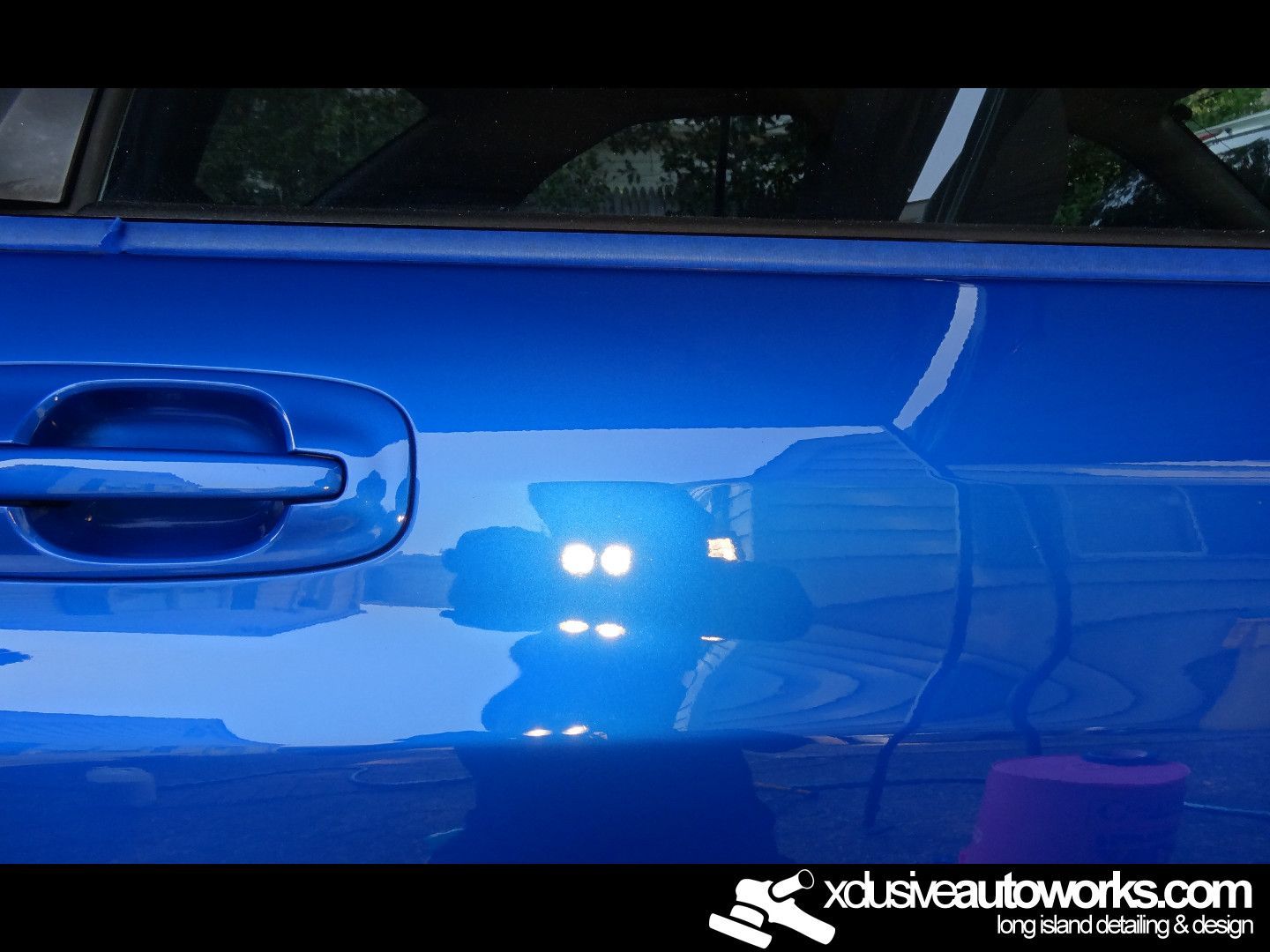A blue car with the website xdusveautoworks.com on the bottom
