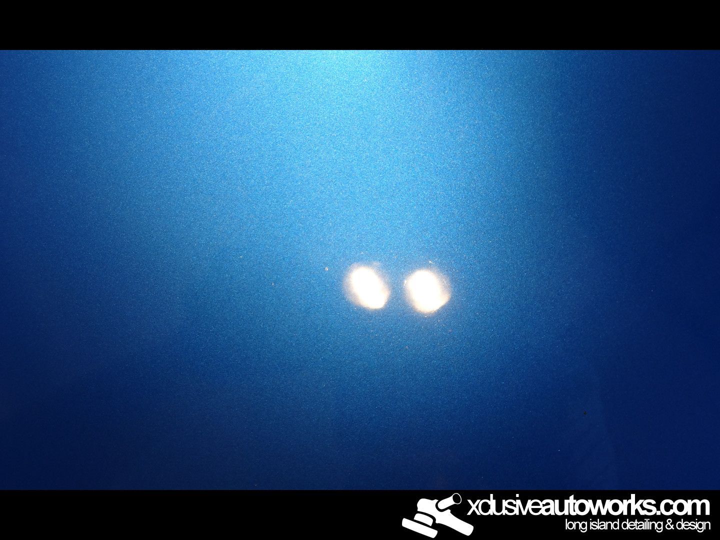 A close up of a blue surface with xclusiveautoworks.com written on the bottom