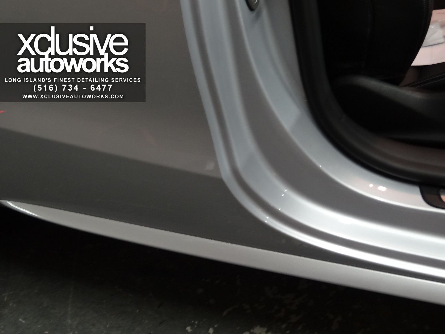A silver car with xclusive autoworks written on the side