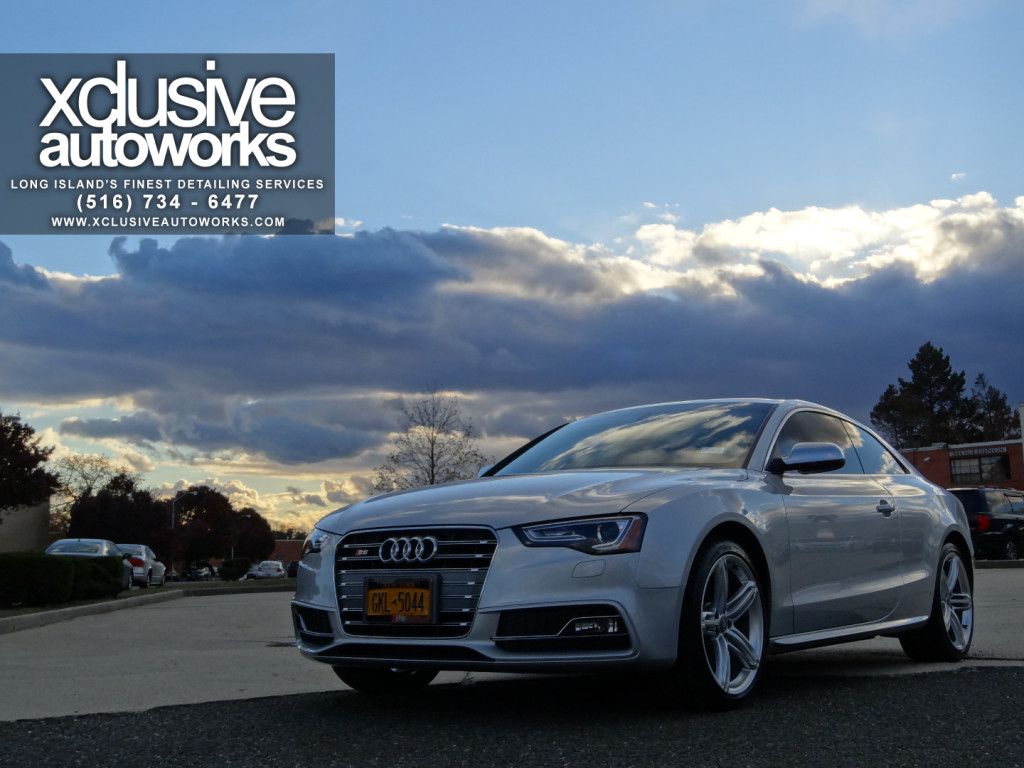 A white audi a5 coupe is parked on the side of the road.