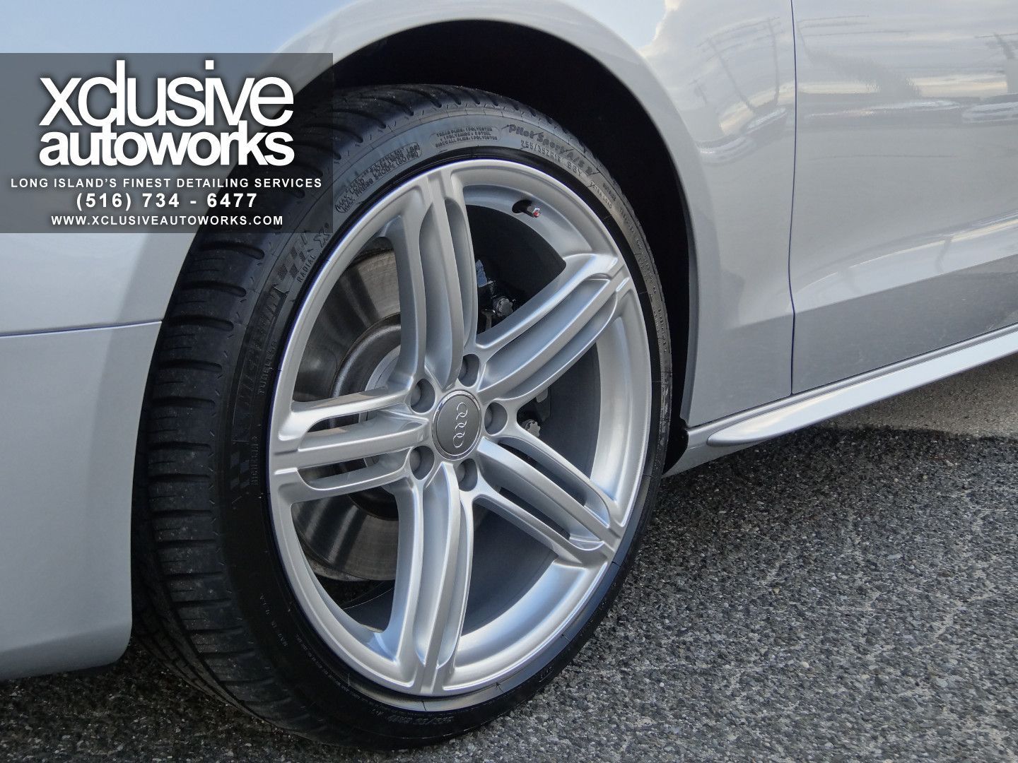 A silver car with xclusive autoworks written on the side