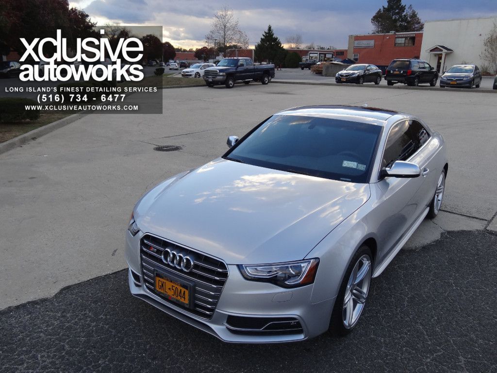 A silver audi is parked in a parking lot by xclusive autoworks
