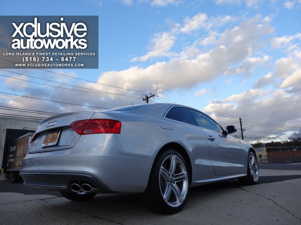A silver audi a5 coupe is parked on the side of the road