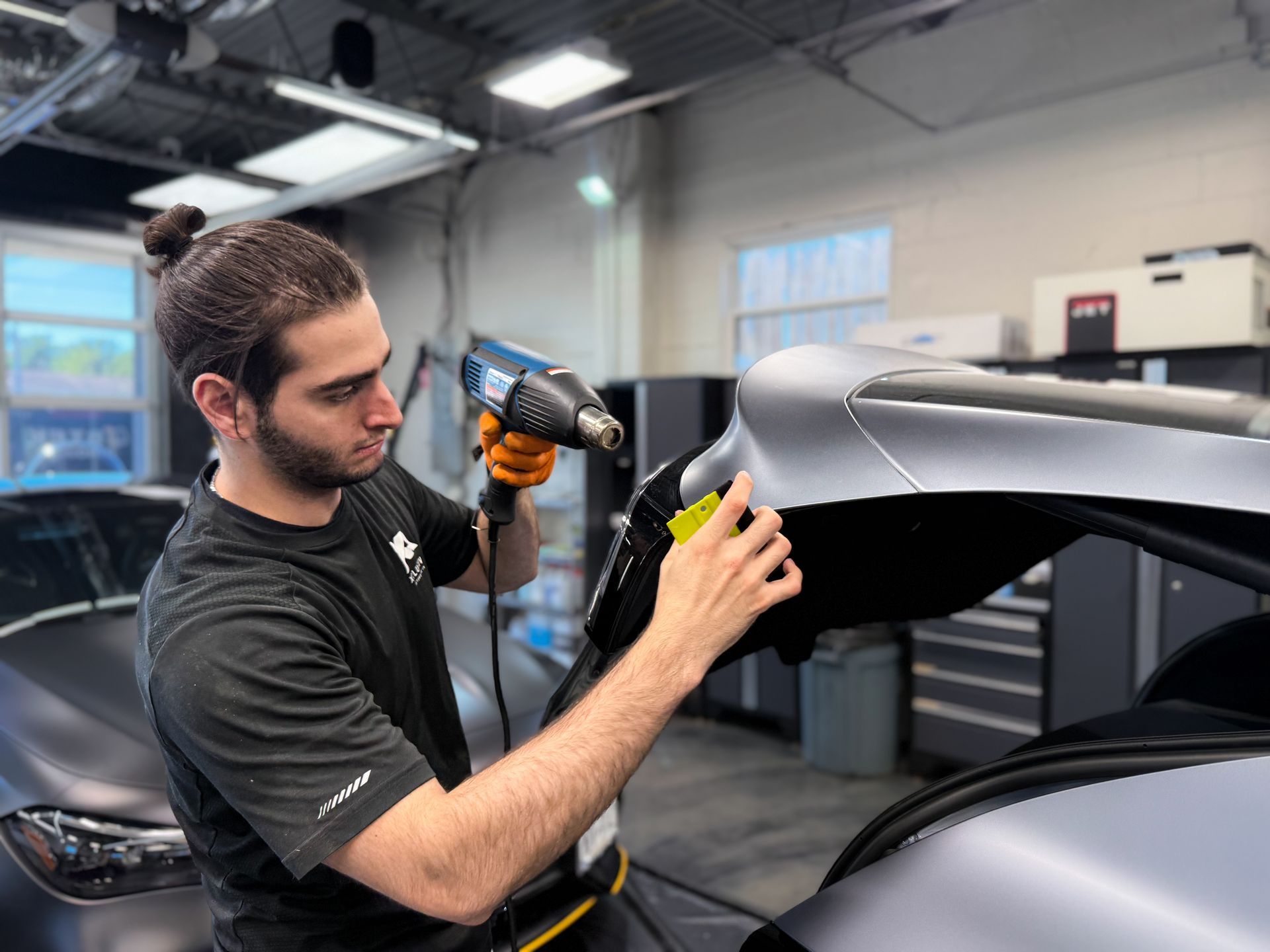 Worker using a power drill to install a car part in an auto shop