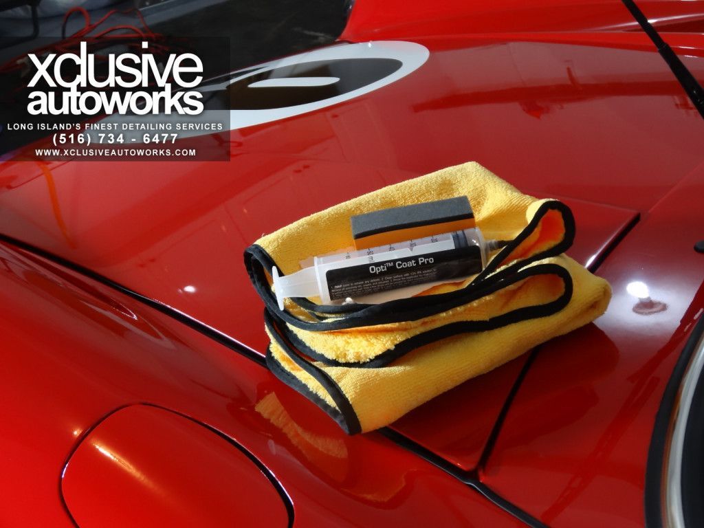 A yellow towel is sitting on the hood of a red car ..
