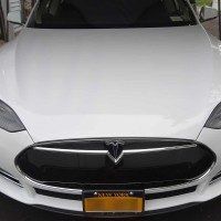 A white tesla model s is parked in a parking lot.