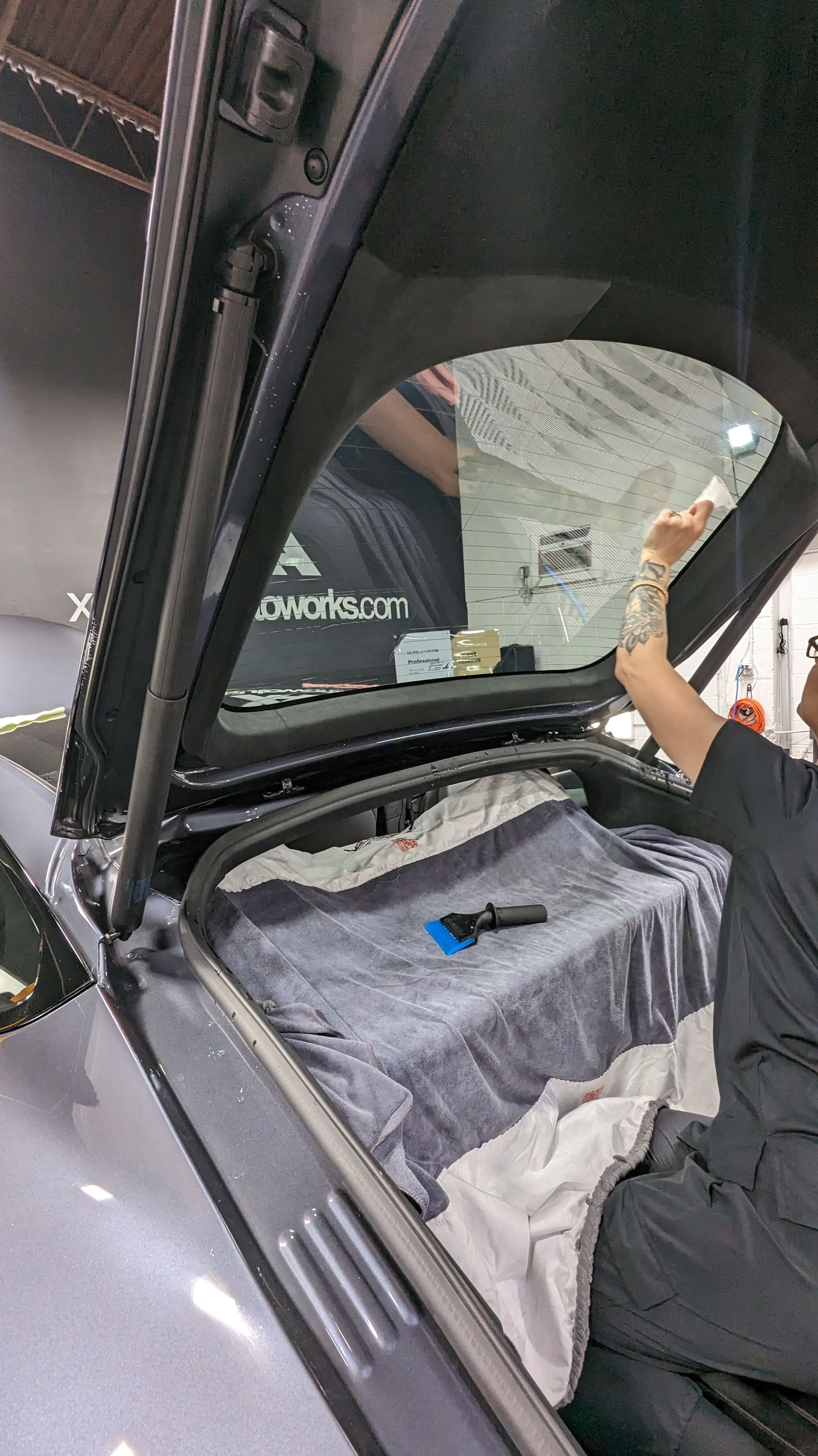 A man is cleaning the windshield of a car with a towel.