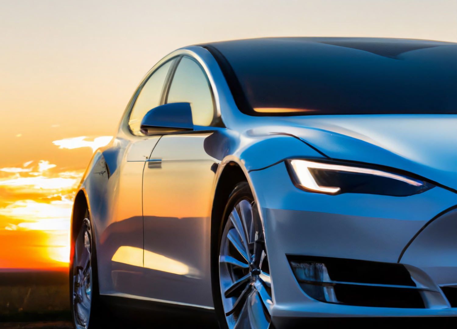 Tesla at sunset, front view on a road with orange sky reflections.