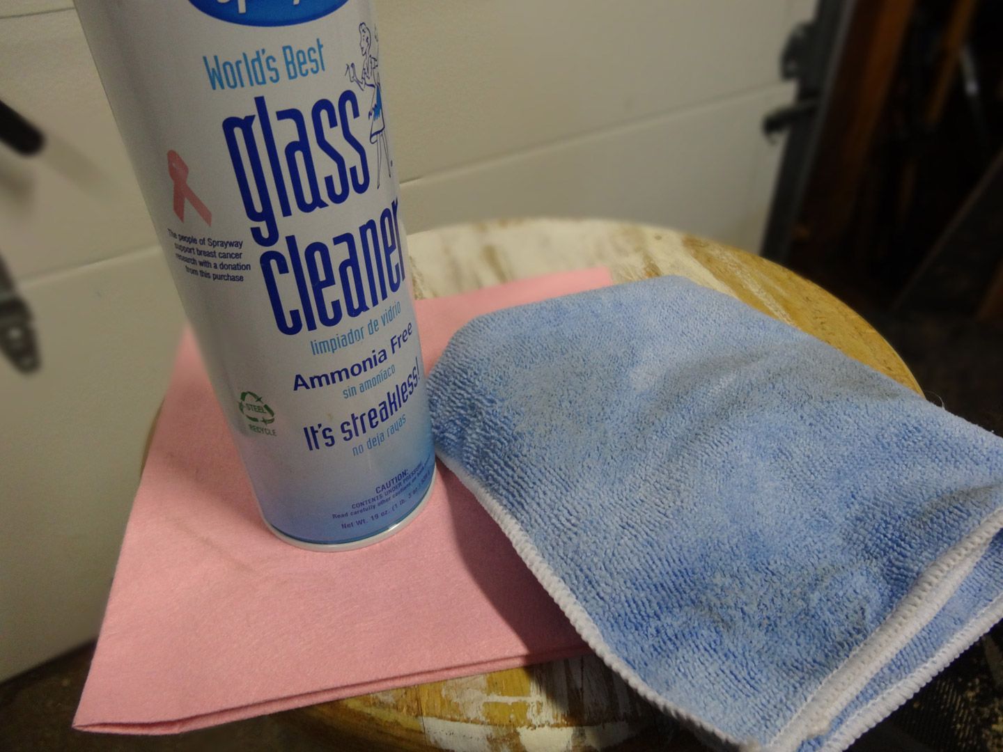 A can of glass cleaner and a cloth on a table