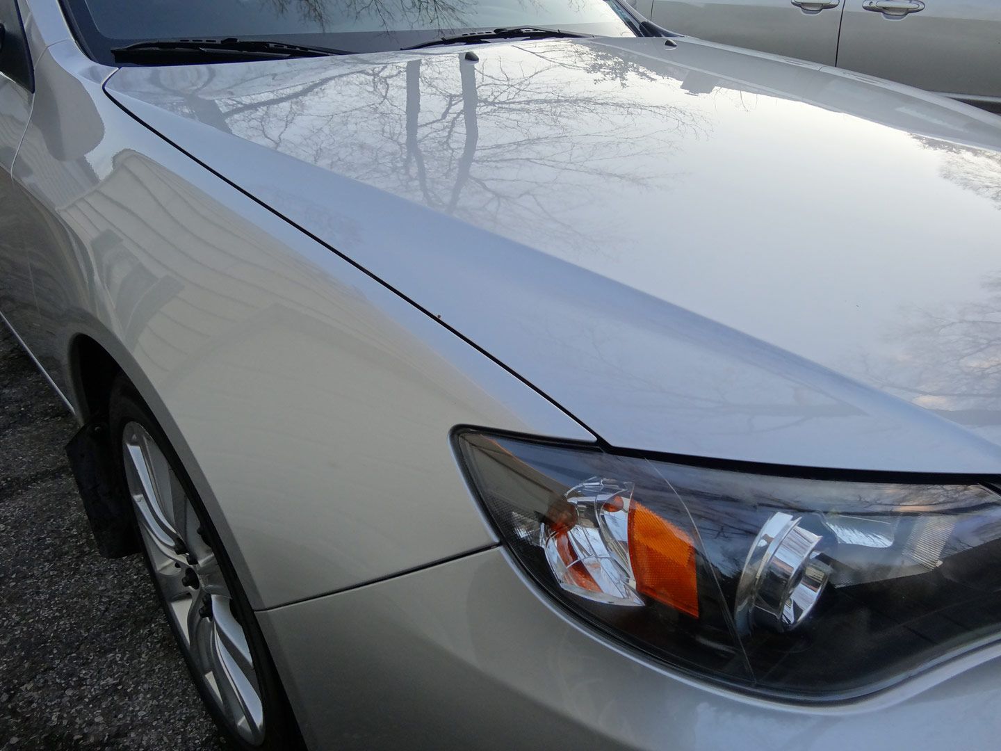 A silver car is parked on the side of the road