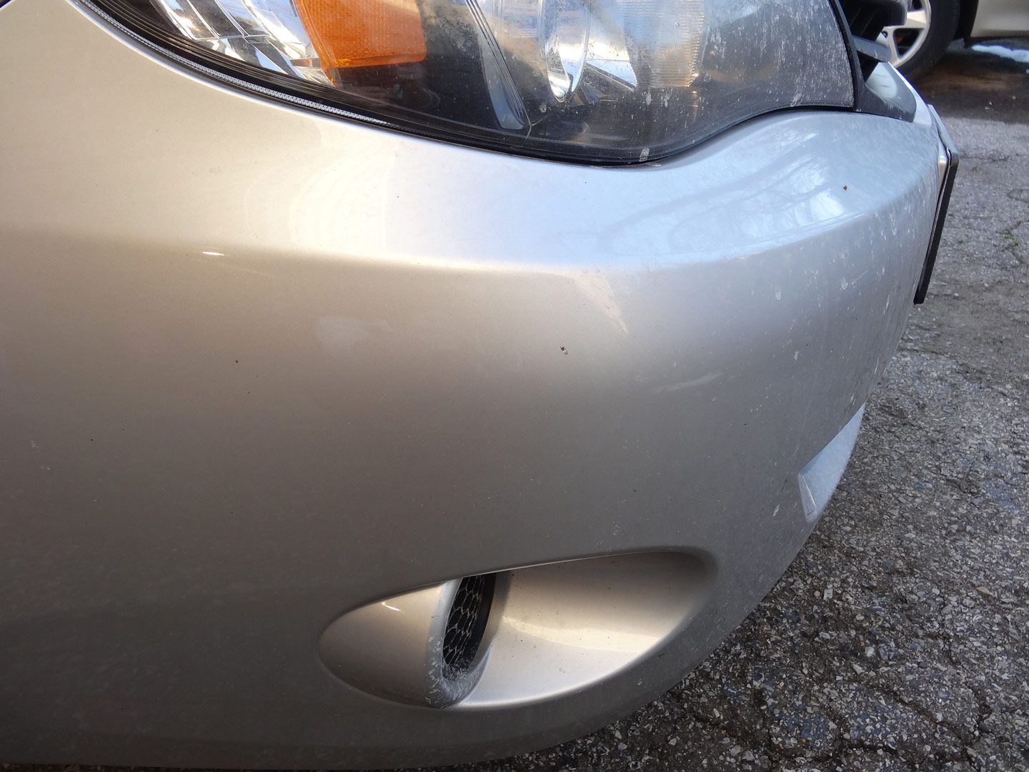 A silver car is parked on the side of the road.