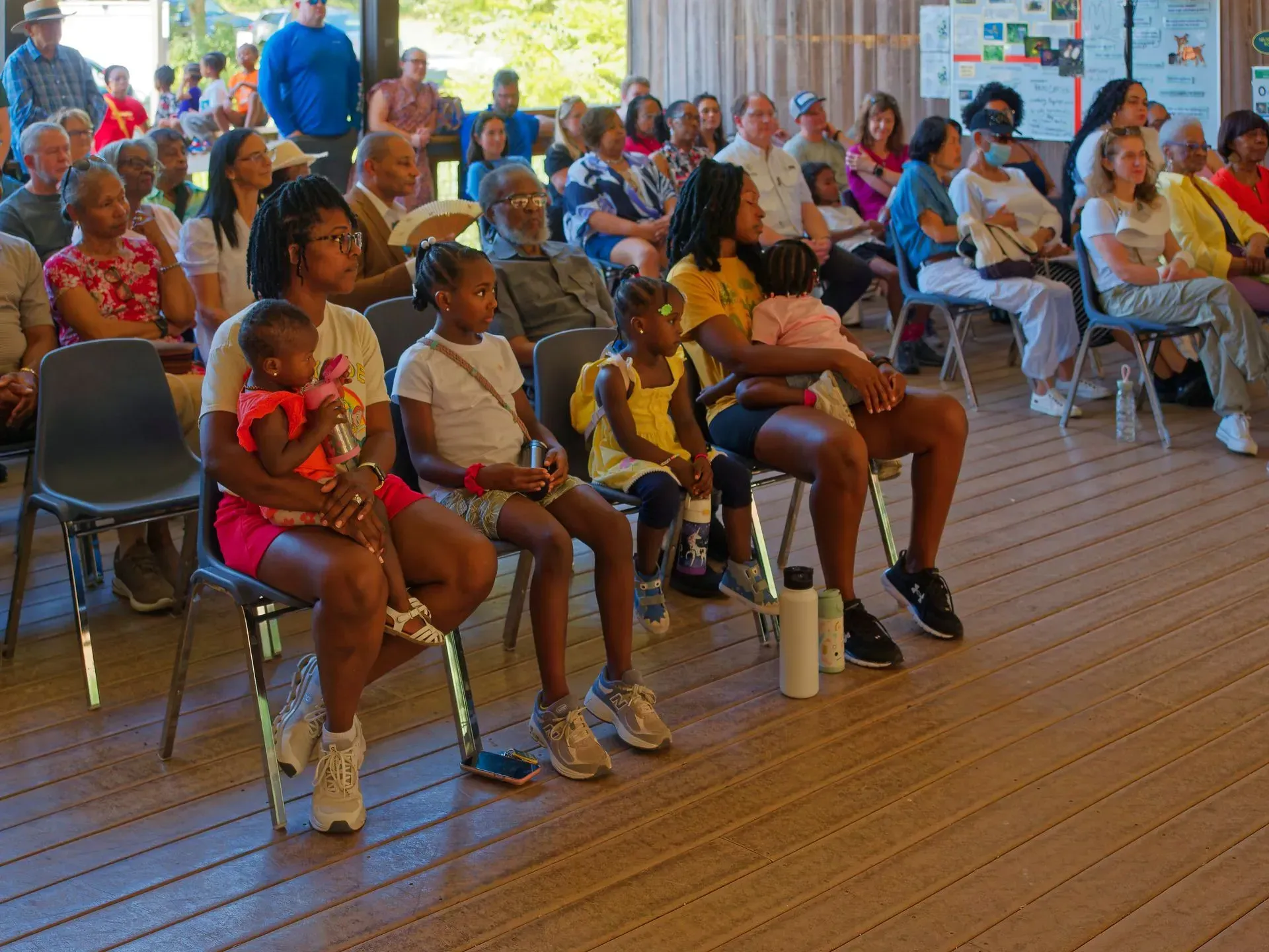 Audience seated in folding chairs at an indoor event, watching attentively.