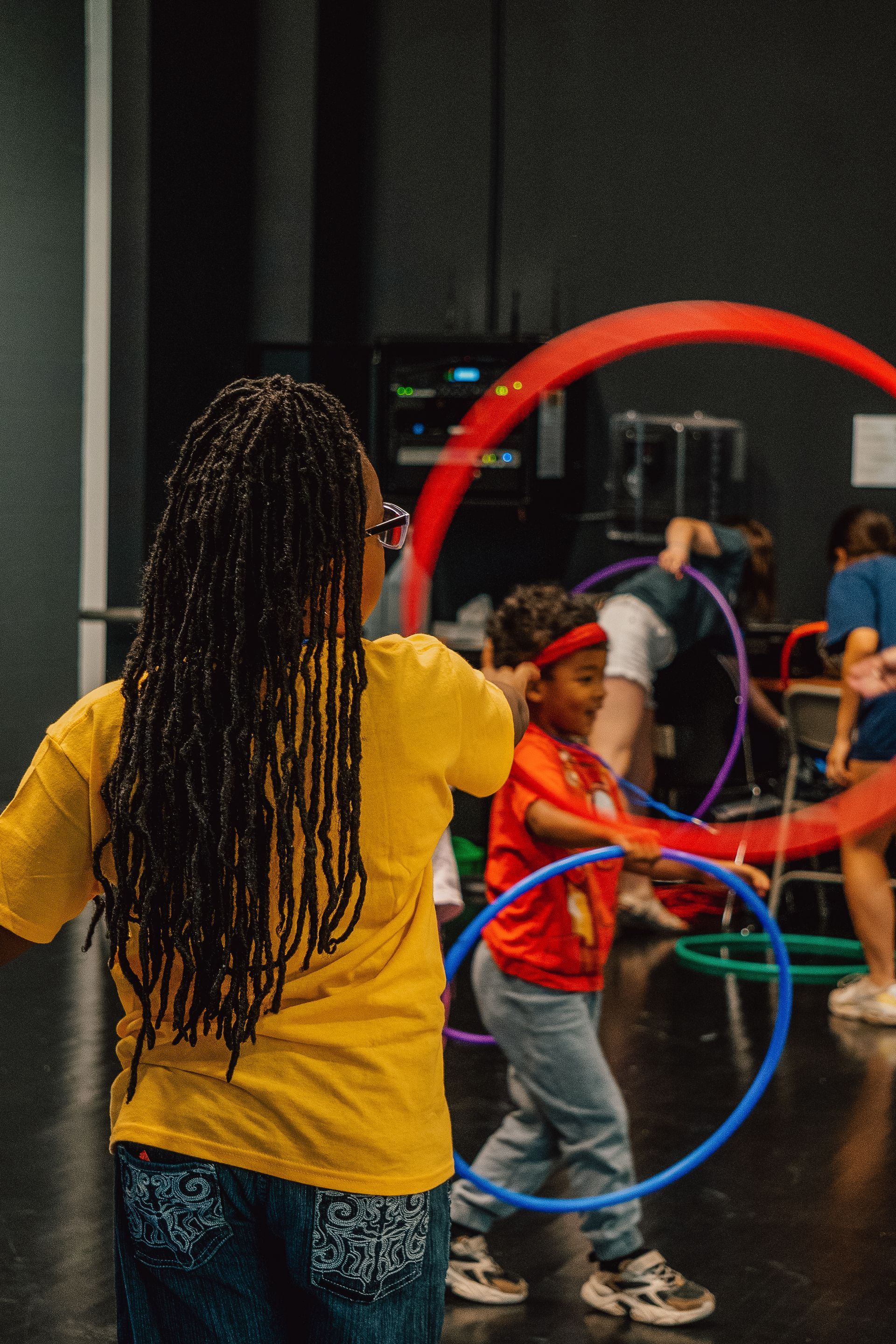 A woman and a boy are playing with hula hoops in a room.