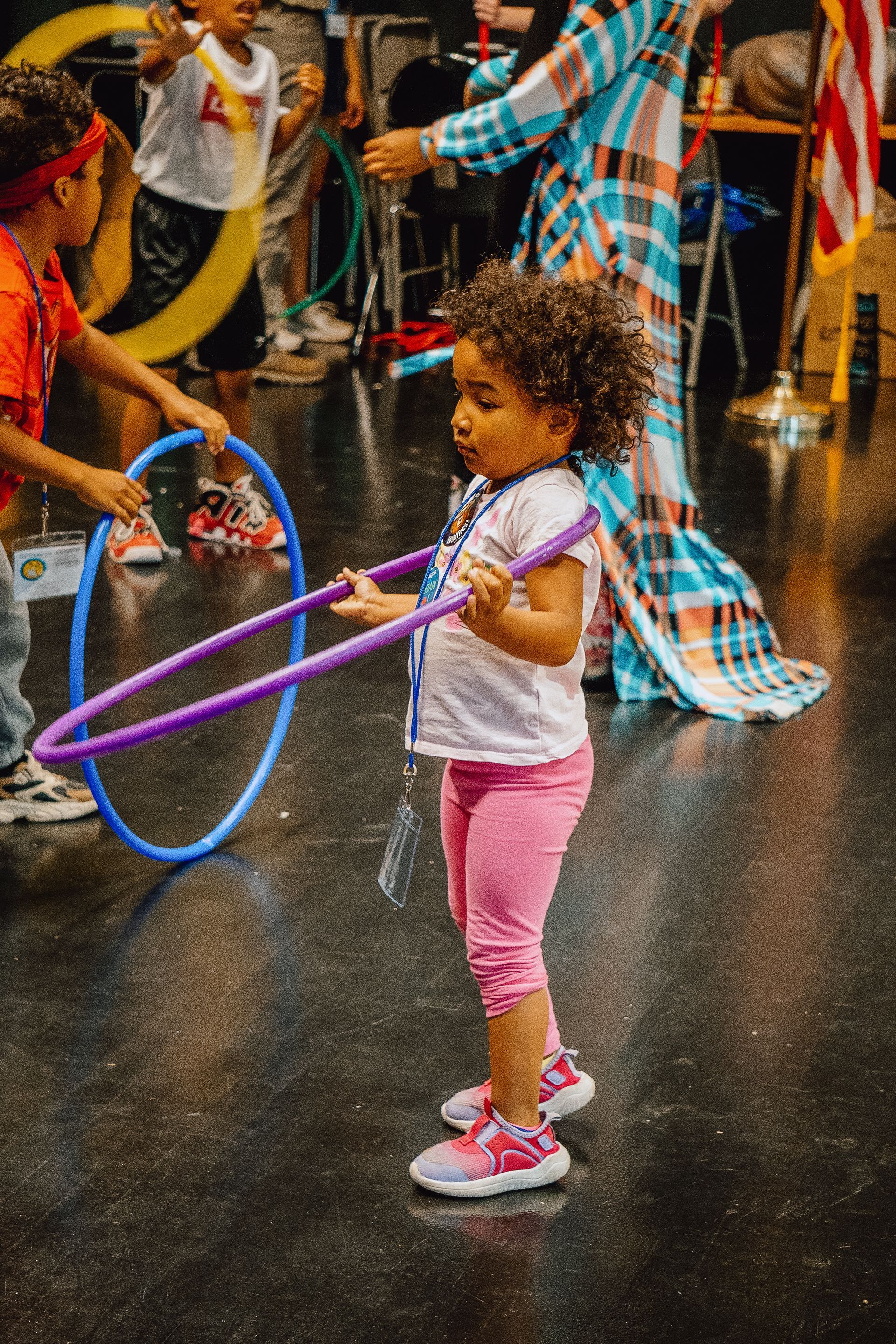 A little girl is playing with a hula hoop in a room.