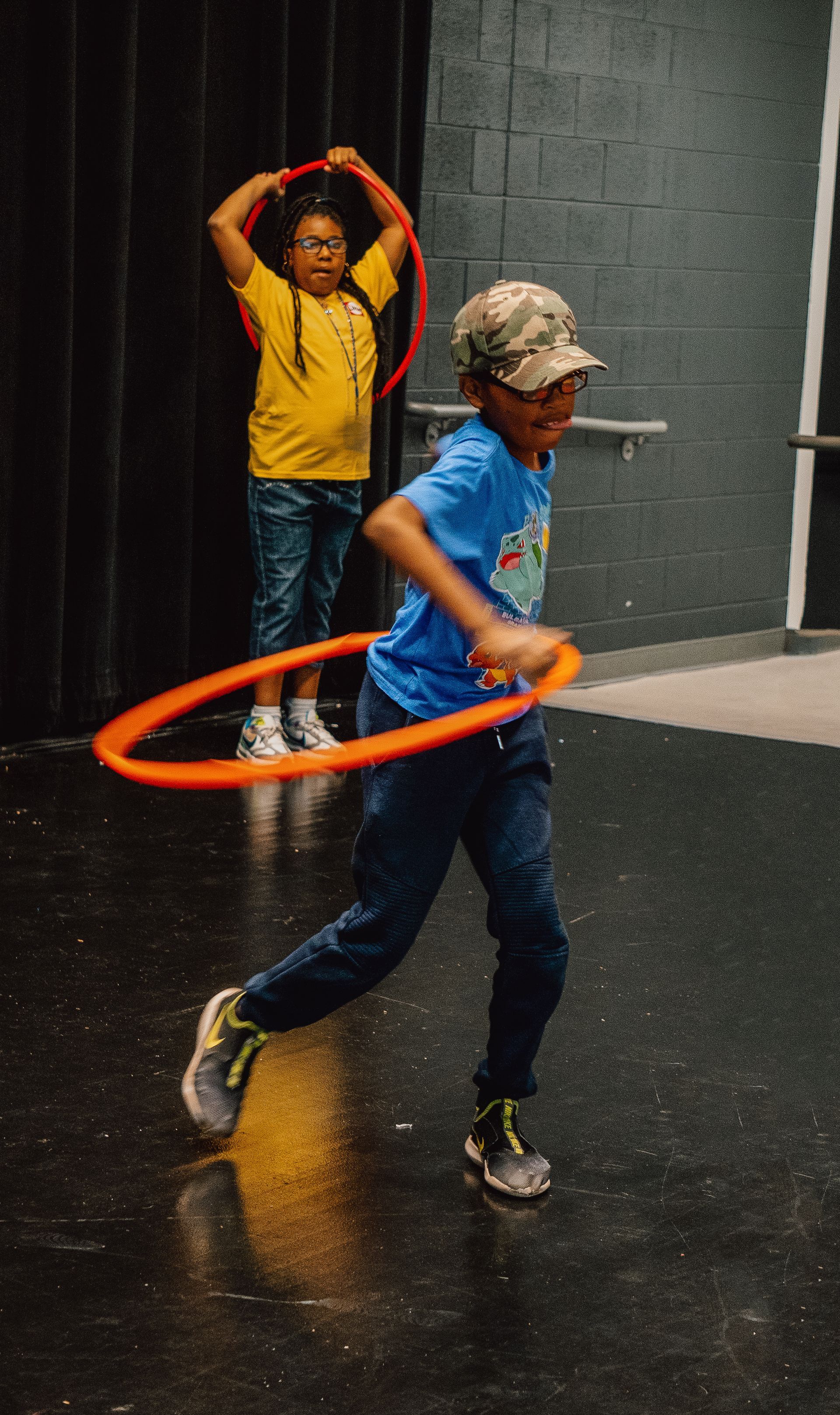 A boy is playing with a hula hoop on a stage.