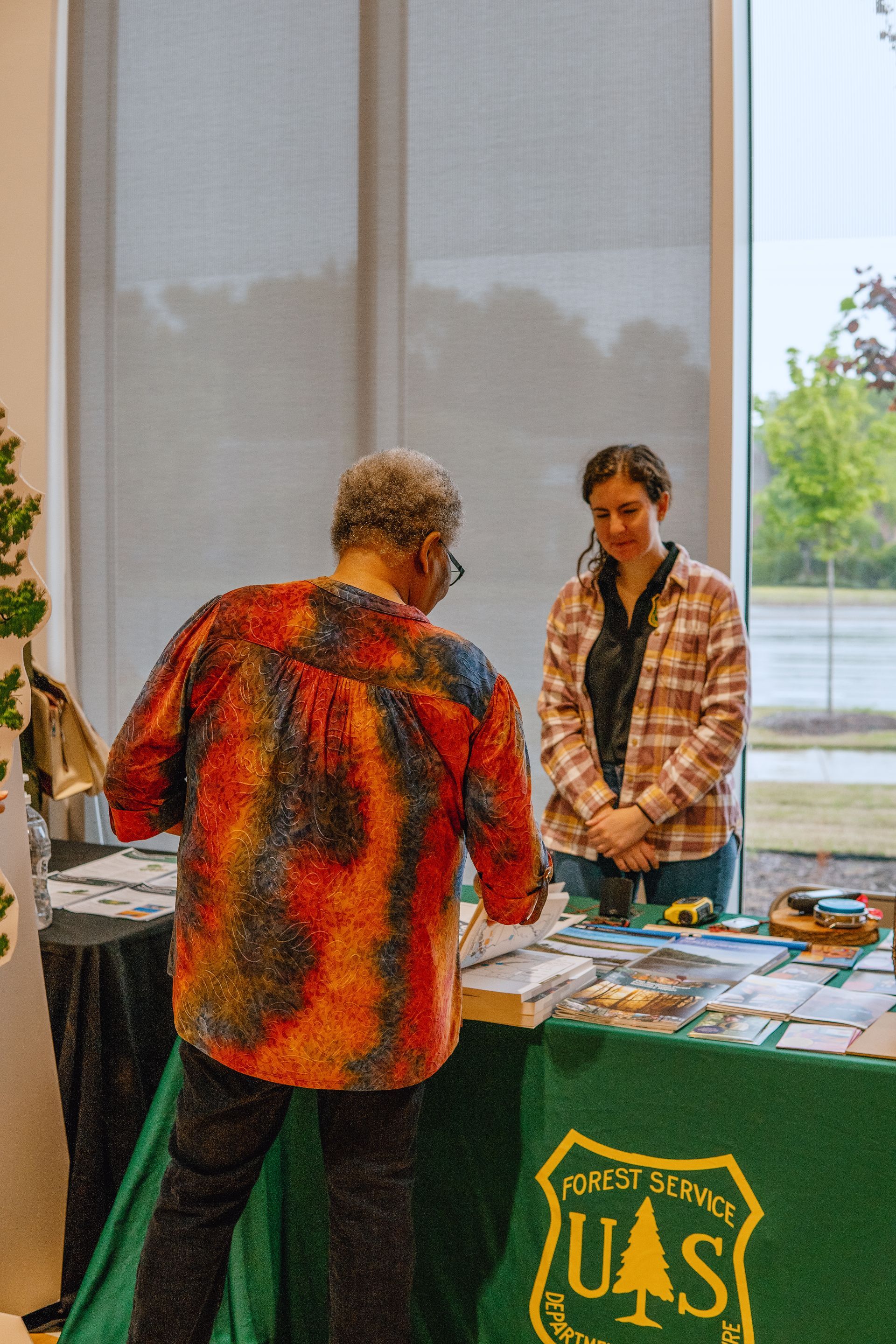 A woman is standing at a table talking to another woman.