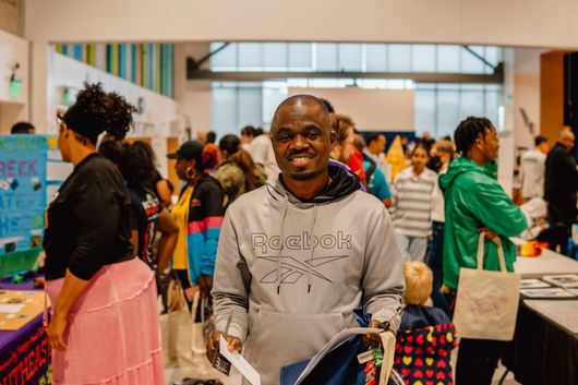 A man is standing in front of a crowd of people at a convention.