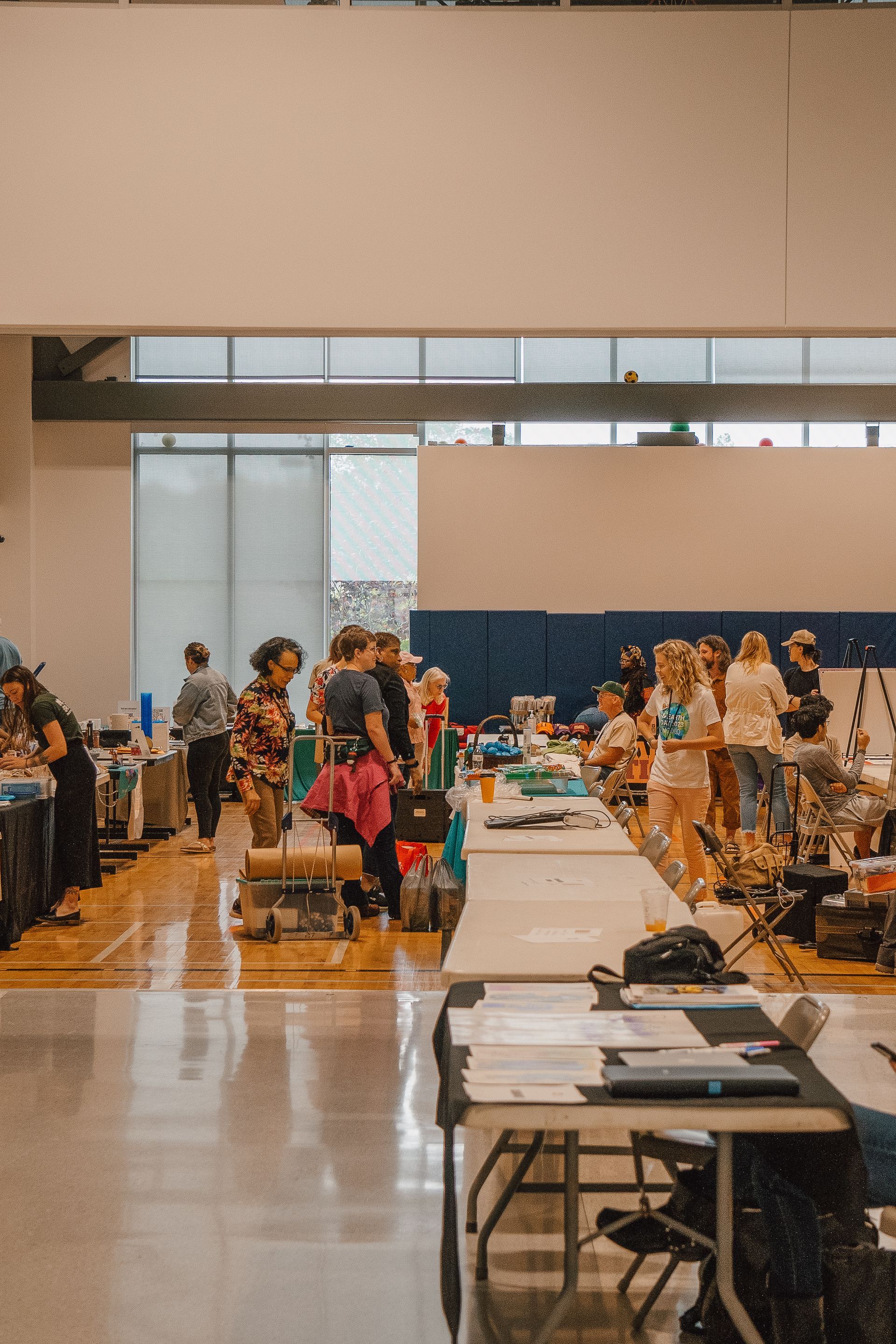 A group of people are standing around tables in a room.