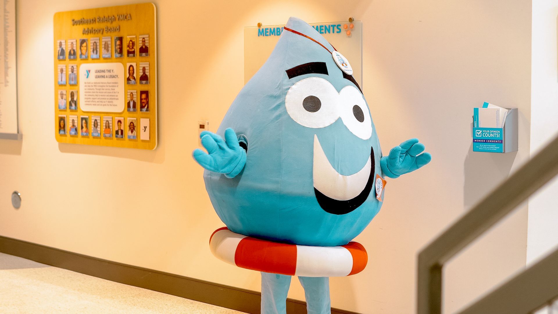 A mascot dressed as a water drop is standing next to a staircase.