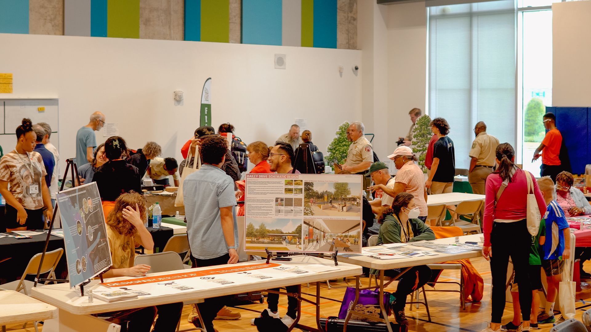 A group of people are standing around tables in a room.