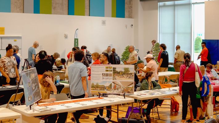 A group of people are standing around tables in a room.