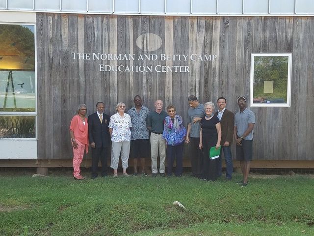 A group of people standing in front of a building that says the norman and betty sam education center