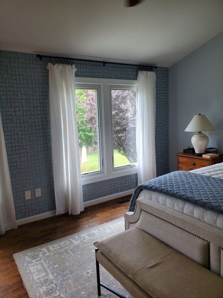A bedroom with a bed , bench , lamp and window.