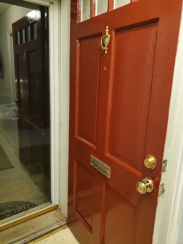 A red door with gold handles is open to a hallway.