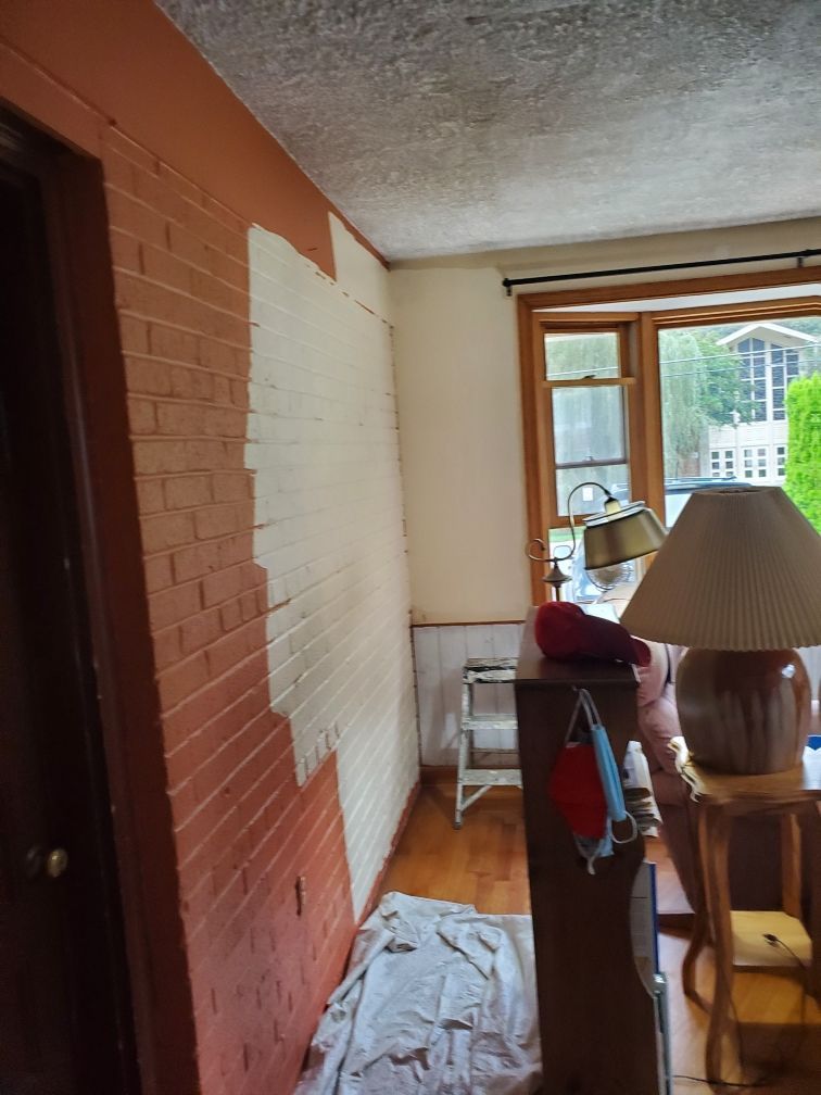 A brick wall is being painted in a living room