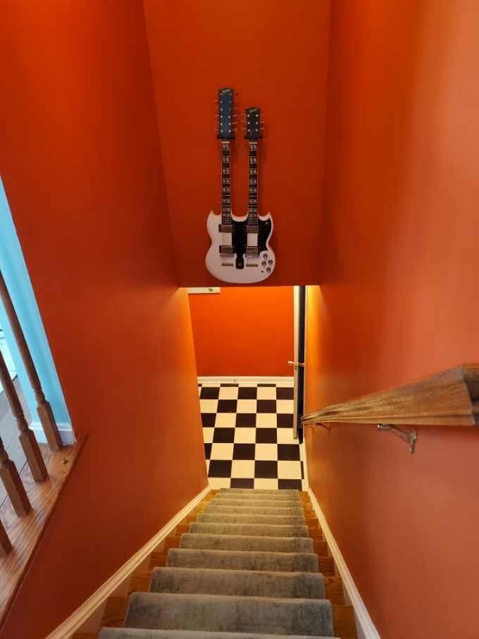 A guitar is hanging from the ceiling of a staircase