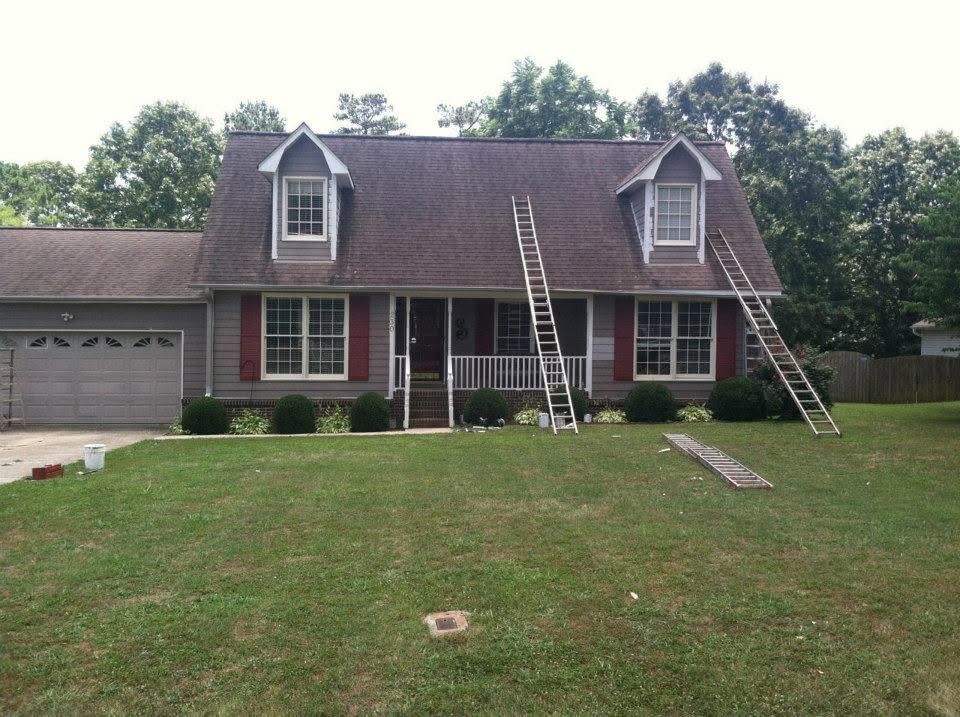 Suburban house with two ladders leaning on the roof and a large front lawn