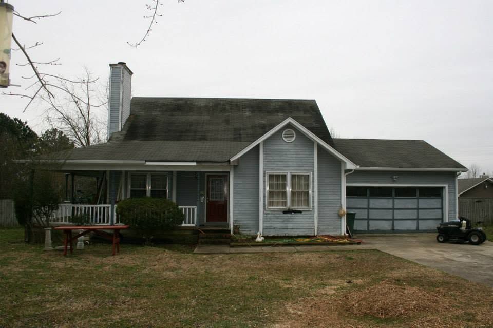 Gray house with front porch, gabled roof, and attached garage on a cloudy day