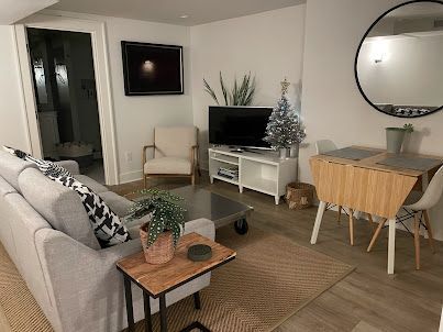 Cozy beige living room with sofa, TV, desk, chair, mirror, and small Christmas tree
