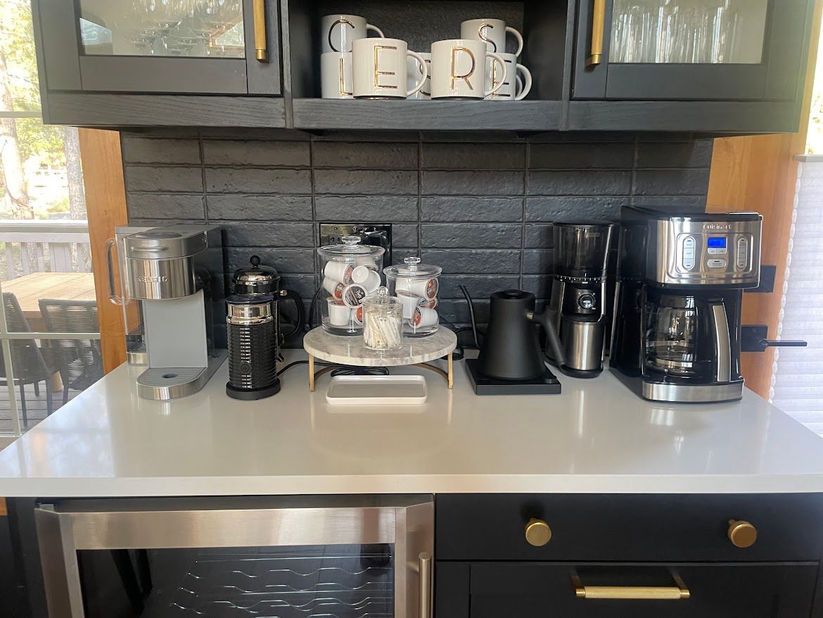 Kitchen coffee station with mugs, espresso machine, grinder, and coffee maker on a counter