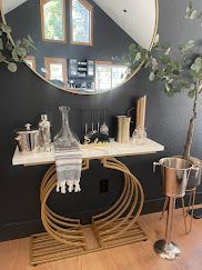 Decorative bar cart with mirror, glassware, bottles, and plant in a cozy room