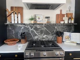 Modern kitchen stove with marble backsplash, wooden shelves, and countertop decor