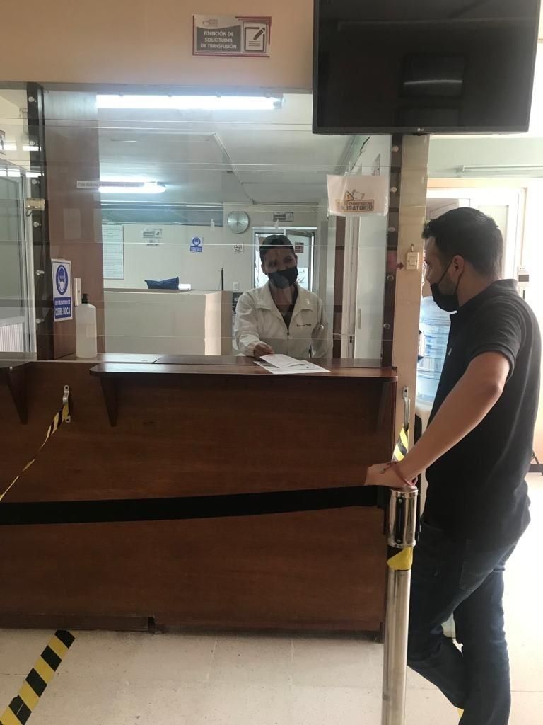Un hombre con una máscara está parado frente a un mostrador en un hospital.