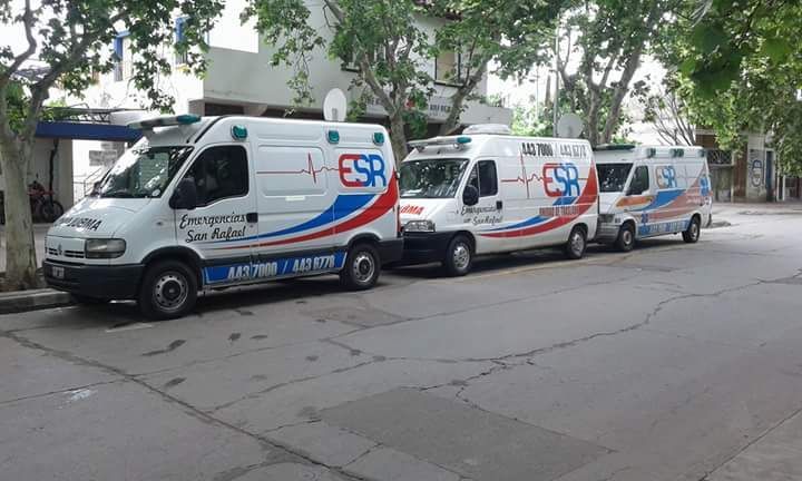 Tres ambulancias blancas de Emergencia San Rafael (ESR) estaban estacionadas en fila en una calle arbolada de la ciudad.