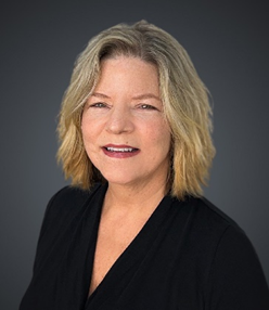 A Cynthia in a black shirt is smiling in a black and white photo.
