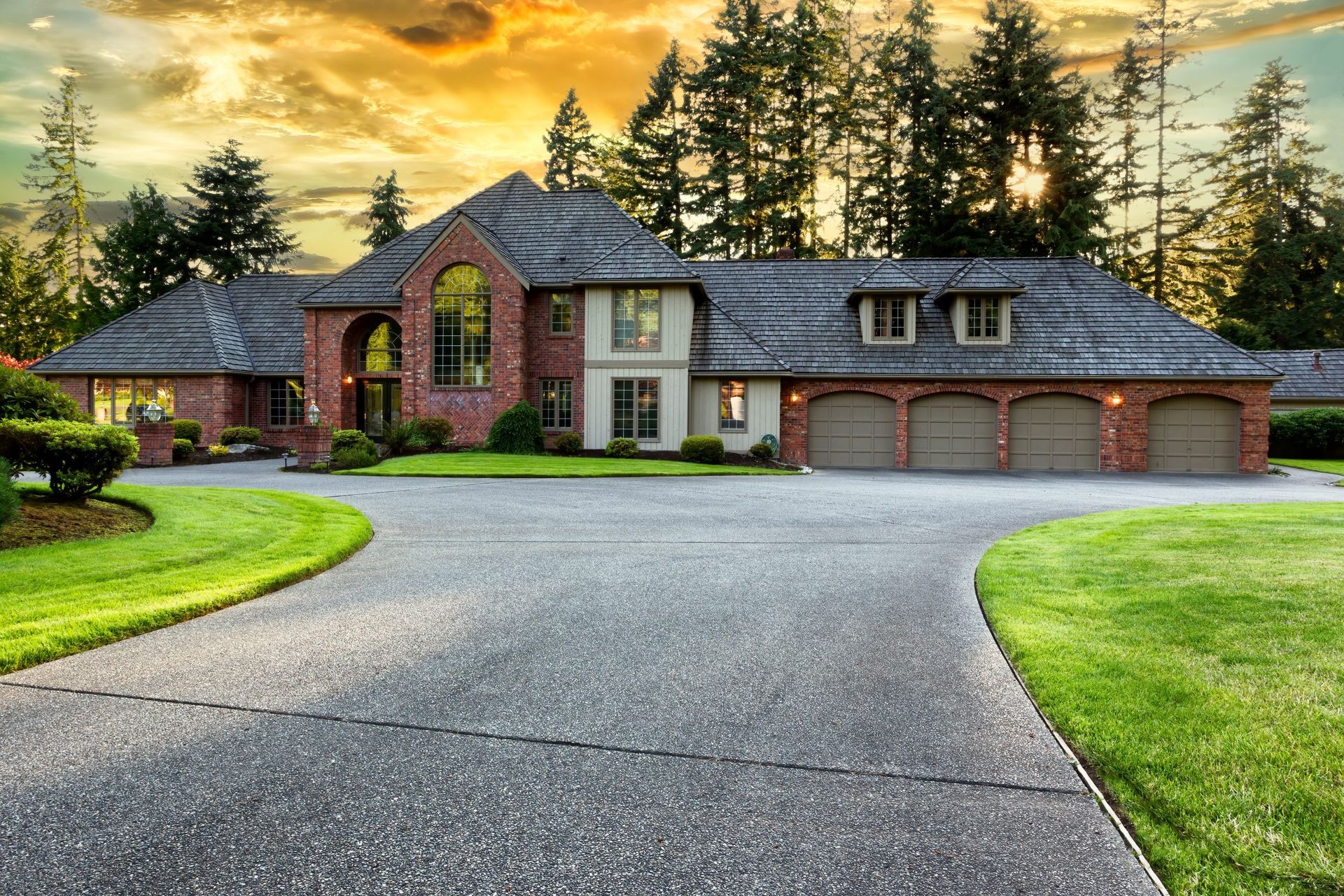 Large brick house with a curved driveway and three-car garage at sunset