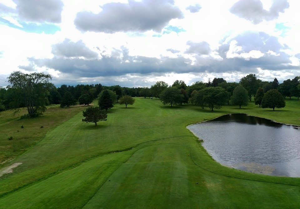 An aerial view of a golf course with a pond in the middle.