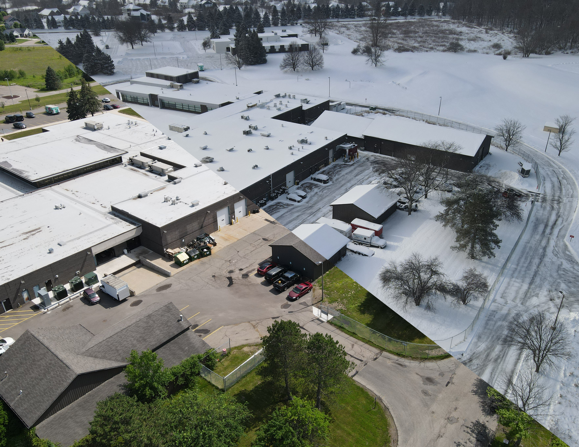 Aerial view of a snow-covered building complex and parking lot with roads and trees nearby
