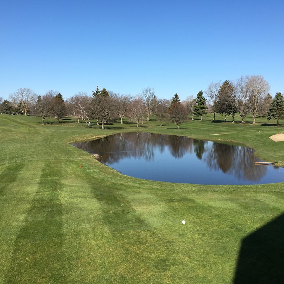 A golf course with a pond in the middle of it